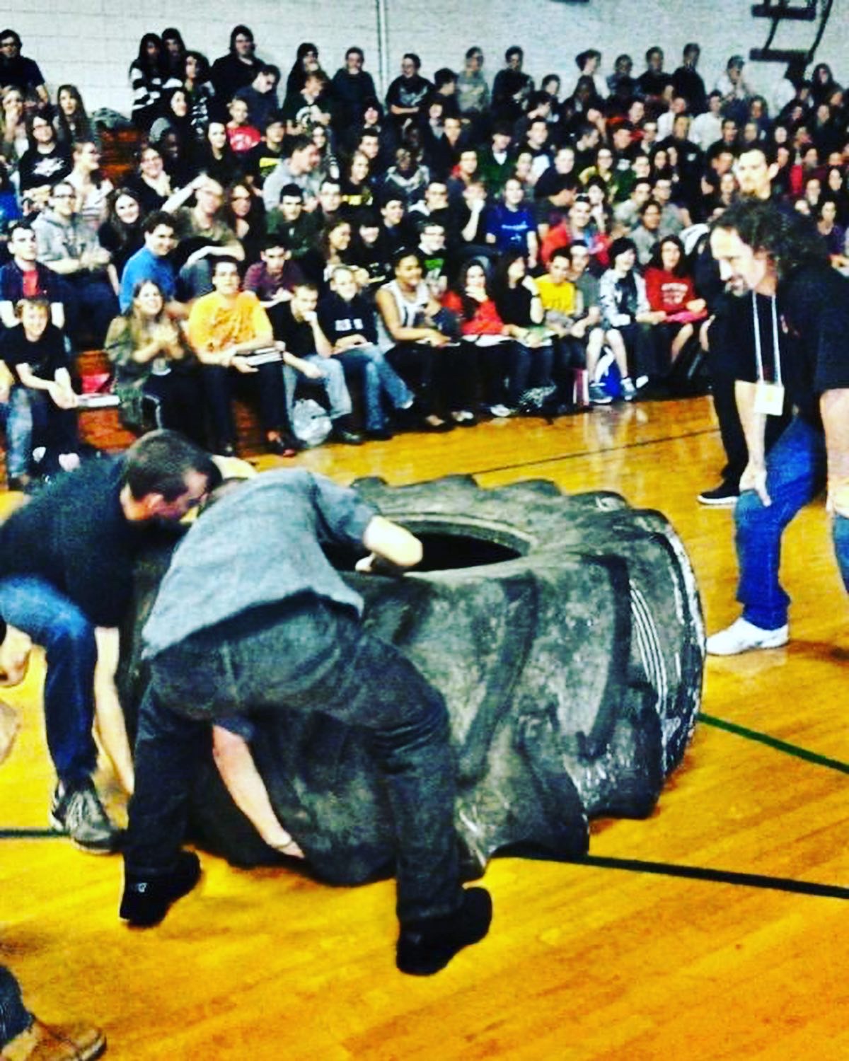 Crowd watching a tire flip challenge in a gymnasium