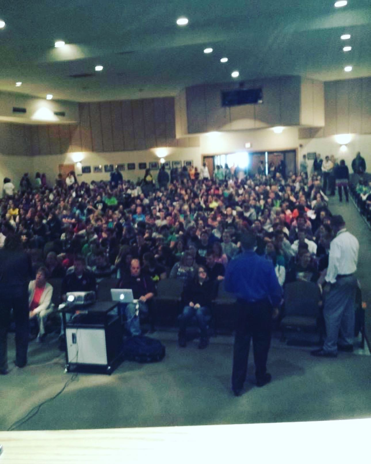 Justin speaking to a packed auditorium of students